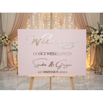 Tablica powitalna w kolorze pudrowego różu z lustrzanymi srebrnymi napisami