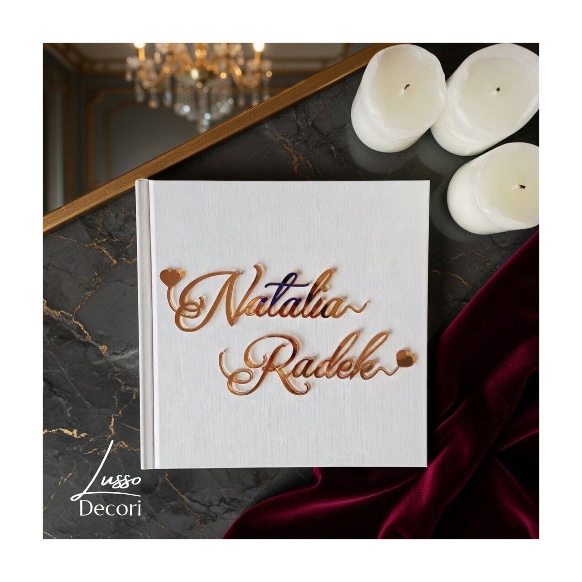 Biała kwadratowa księga gości z lustrzanymi złotymi imionami wykonanymi ozdobną czcionką.